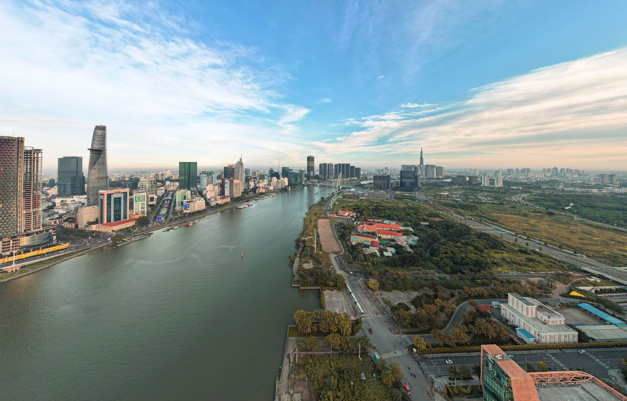 Ho Chi Minh City along the Saigon River seen from above, towers crowding the west bank and open ground on the east