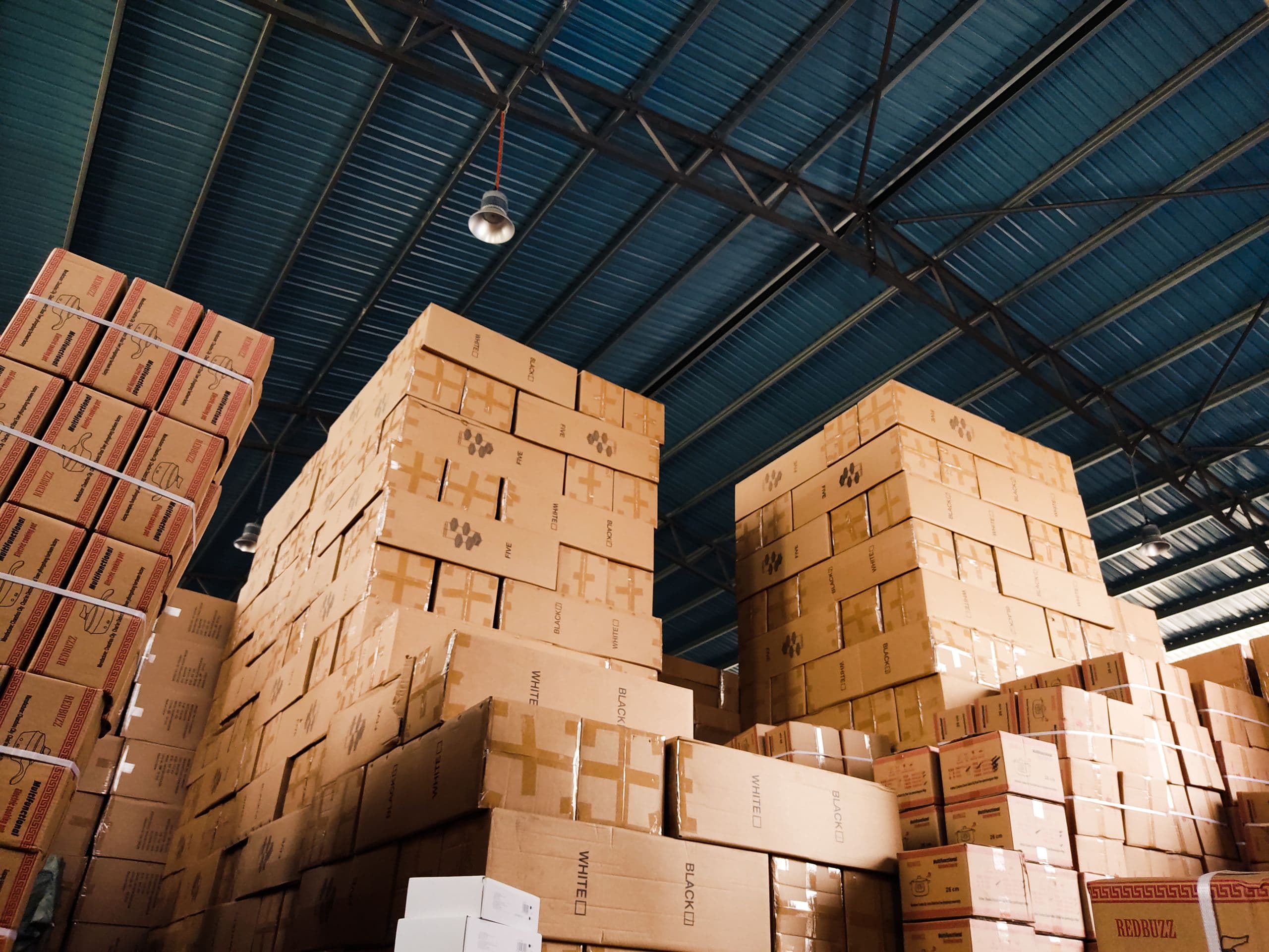 Export cartons stacked in blocks to the roof of a warehouse, strapped and marked, seen from the floor looking up