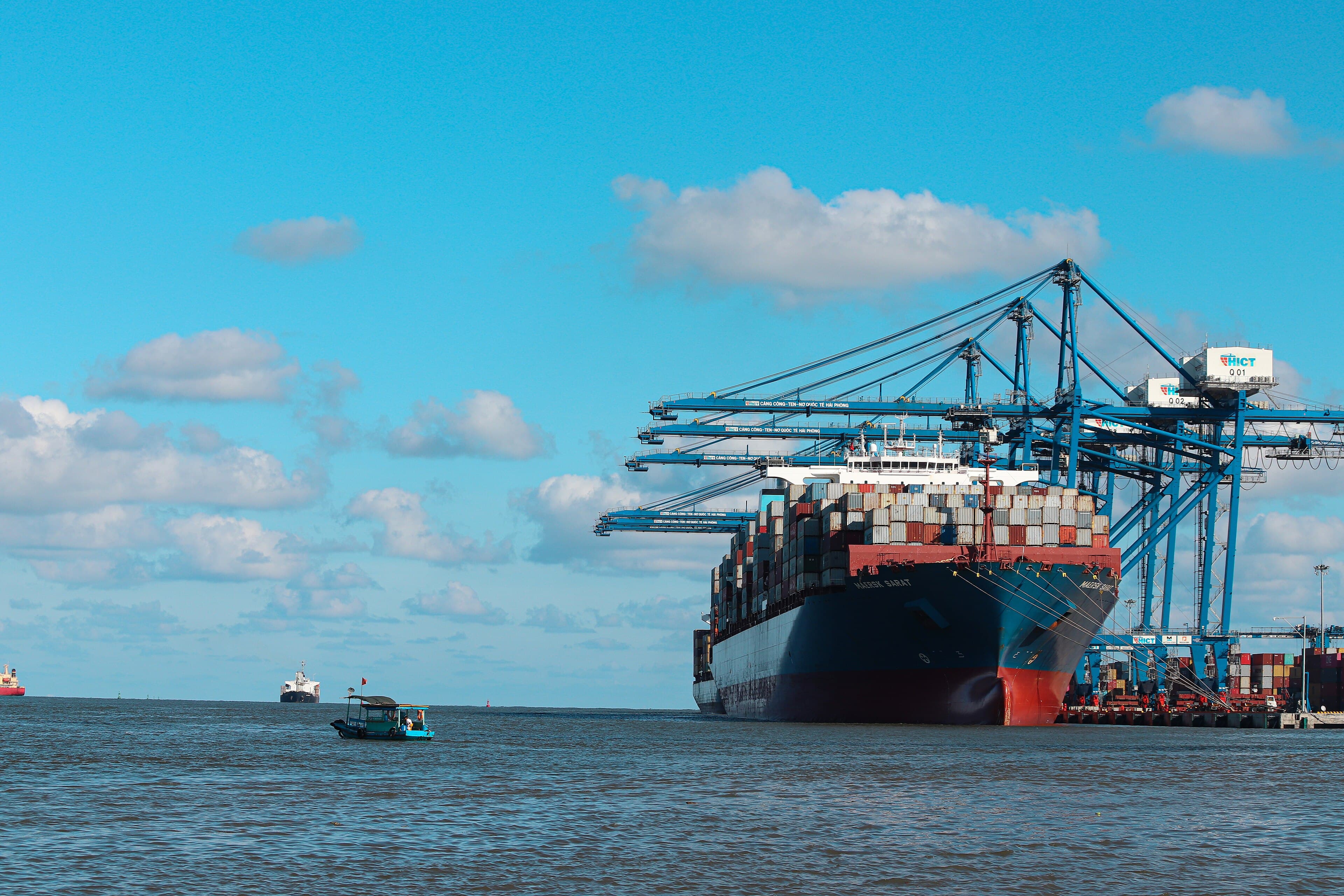 A loaded container ship alongside gantry cranes at a Vietnamese container terminal