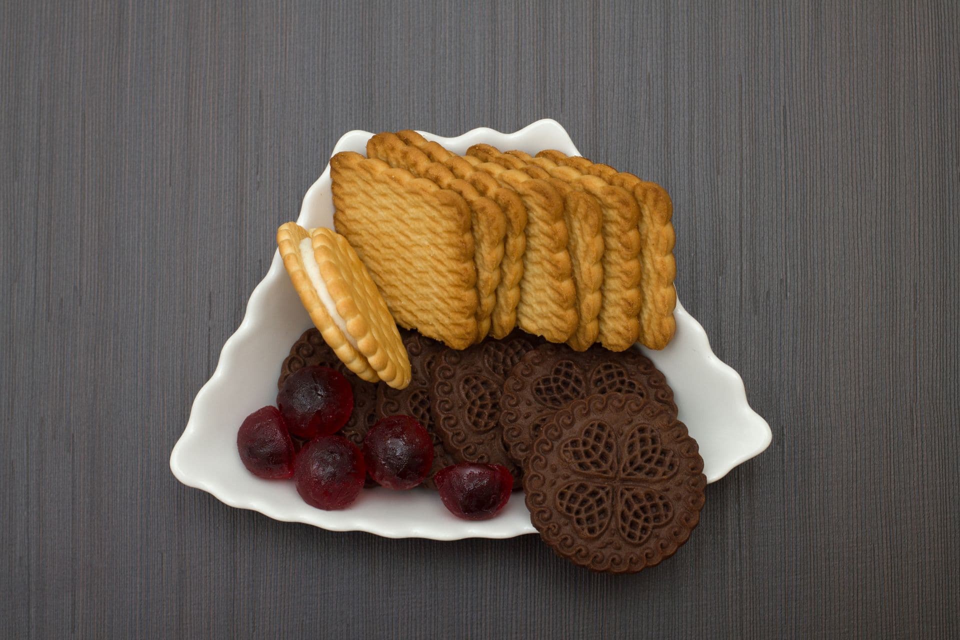 Close-up of various biscuits with colorful gumdrops on a decorative plate