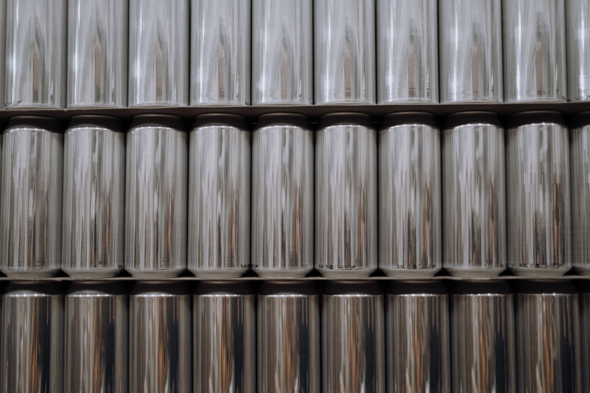 A neatly organized stack of reflective aluminum beverage cans in an industrial setting