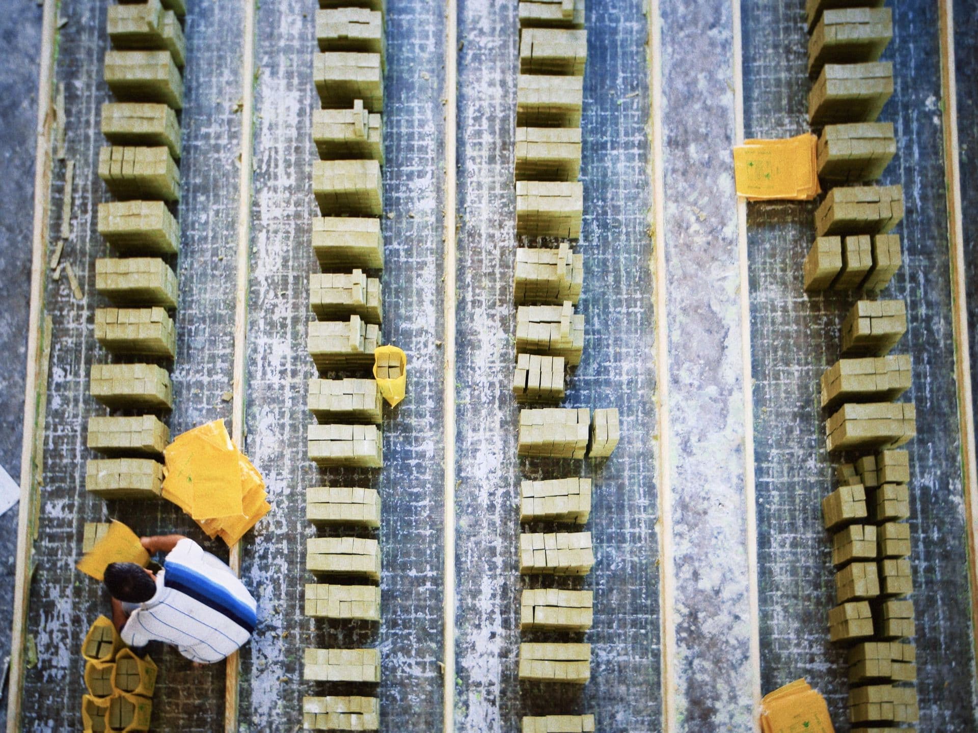 Aerial shot of a worker in a soap factory organizing bars of soap on production lines.