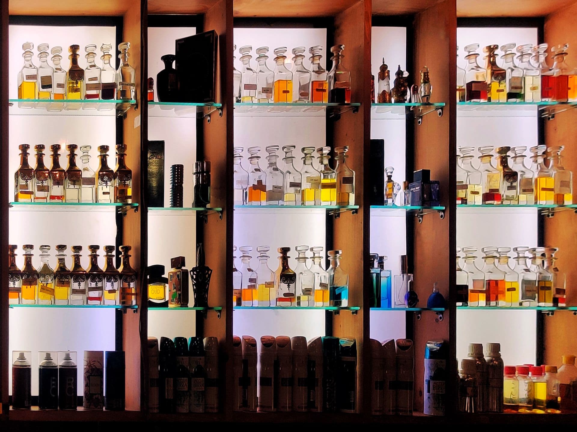 A stylish arrangement of various perfume bottles on shelves, with glass and wood elements, perfect for fragrance enthusiasts.