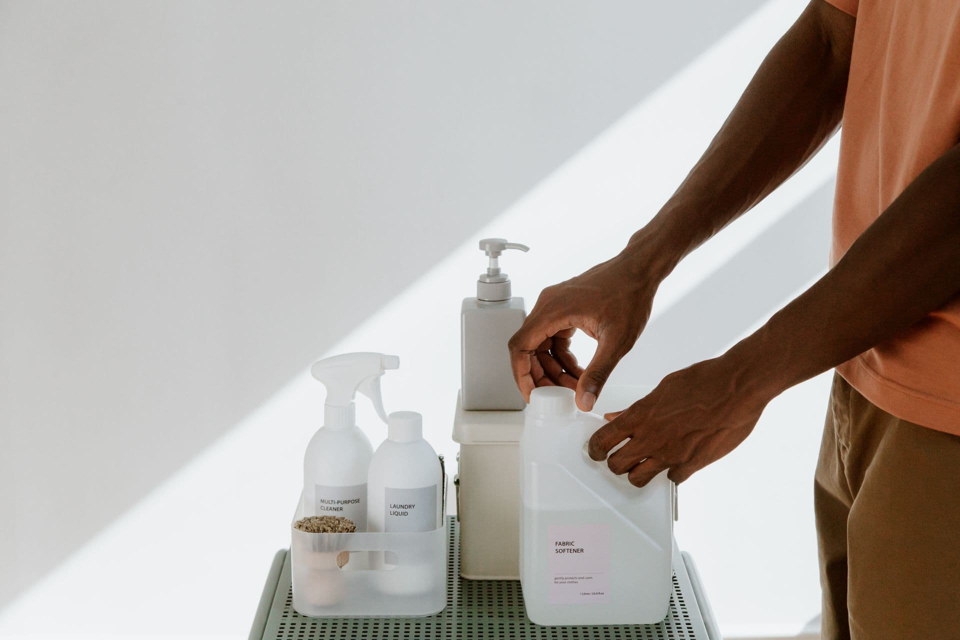 Man arranging cleaning products on a shelf, highlighting tidiness and organization.