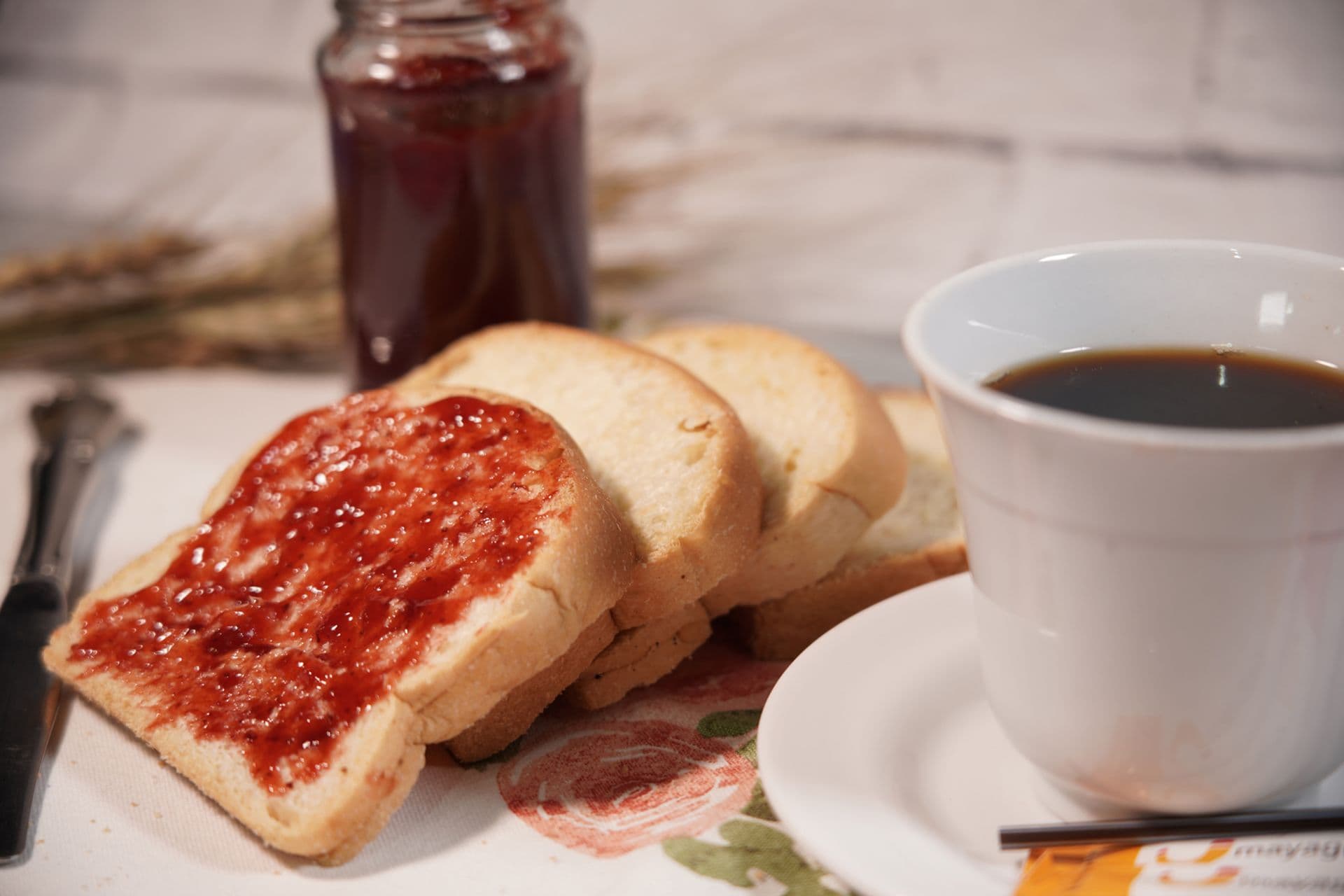 Sliced toast with strawberry jam and a cup of coffee, perfect for a cozy breakfast moment.