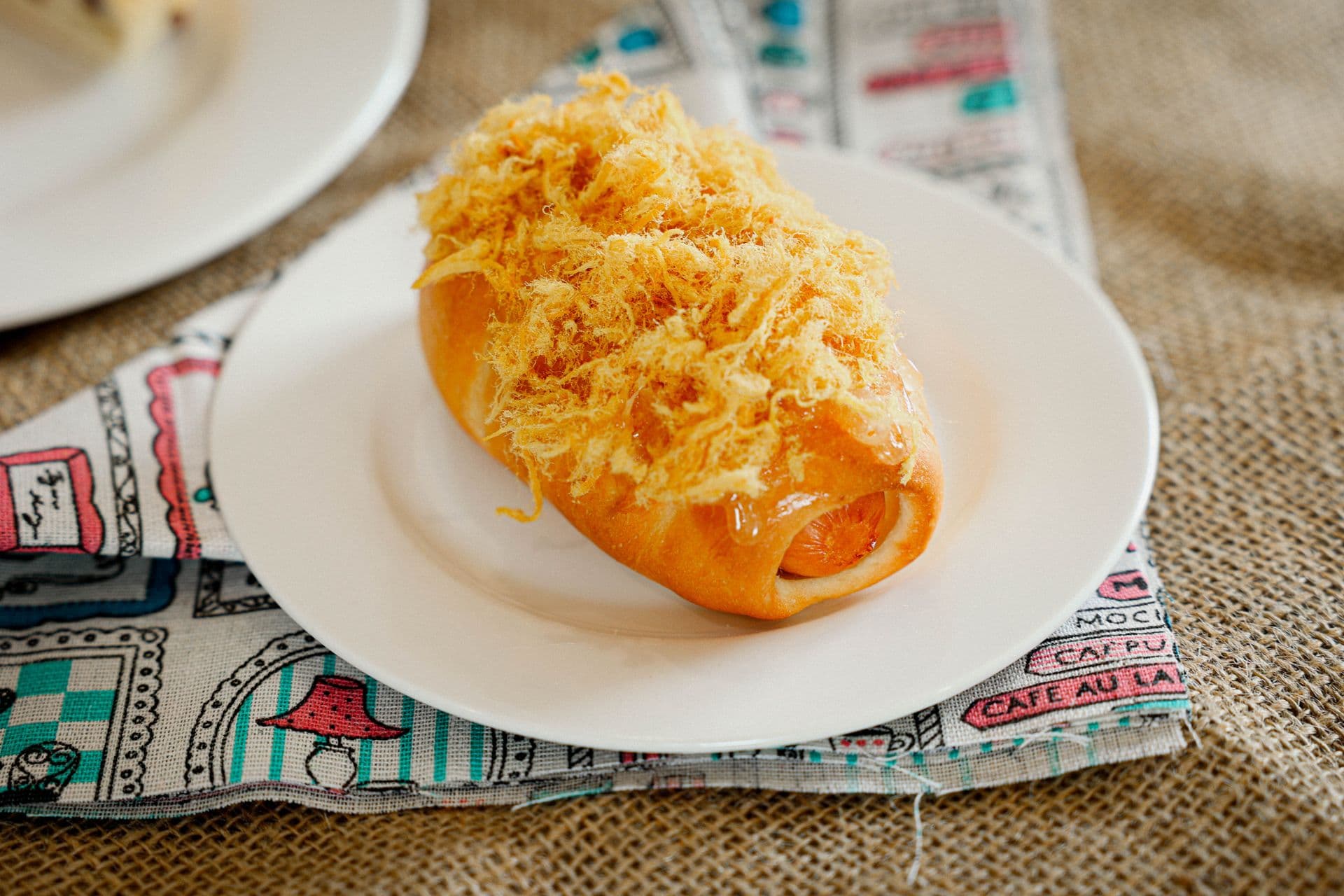 Close-up of a Vietnamese pork floss bun on a white plate in Ho Chi Minh City.