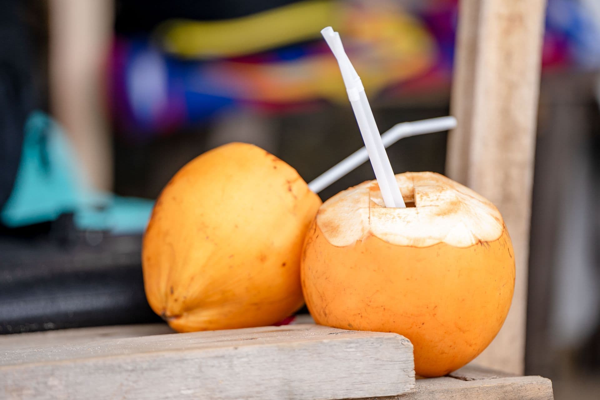 Fresh yellow coconuts fitted with drinking straws